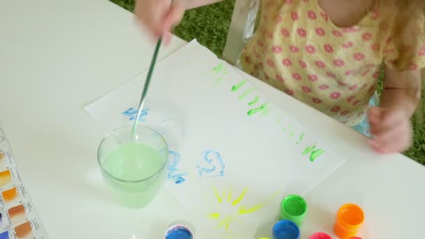 美しい赤毛の少女がテーブルに座っている paintand ブラシと塗料します。 — ストック動画