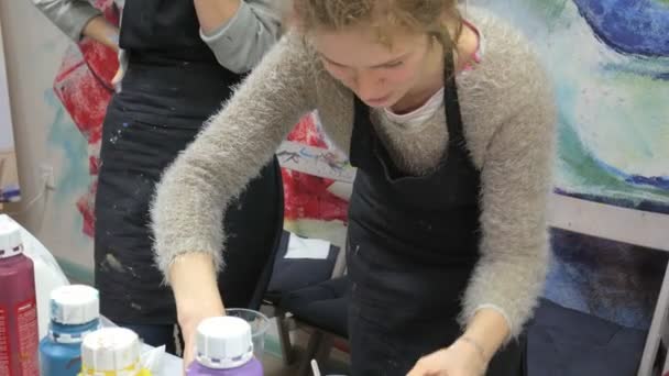 Mulher prepara e pinta tintas para desenhar um quadro de arte fluida — Vídeo de Stock