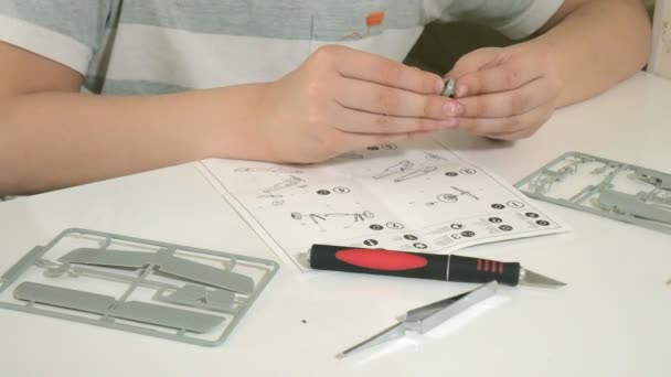 The boy creates a plastic model airplane, an exact copy, from the designer — Stock Video