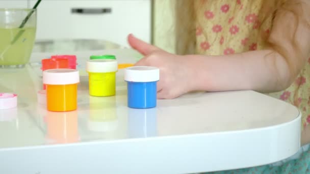 Kleine schöne rothaarige Mädchen malt mit Farbe und Pinsel am Tisch sitzend — Stockvideo