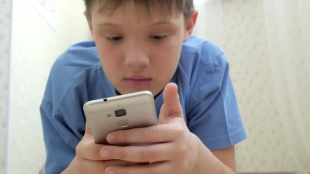 Tonåring spelar spel på smartphone med spänning när du sitter på golvet hemma — Stockvideo