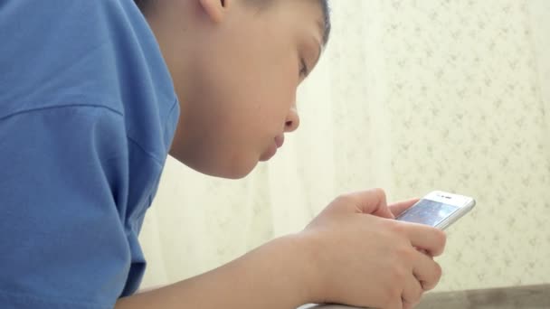 Adolescent jouer à des jeux sur smartphone avec excitation tout en étant assis sur le sol à la maison — Video