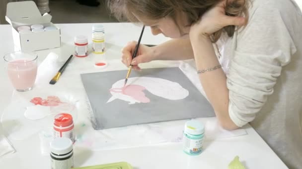 Little beautiful red-haired woman paints with paint and brush sitting at table — Stock Video