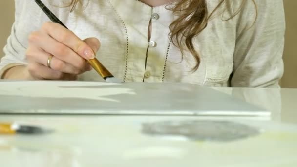 Kleine mooie roodharige vrouw schildert met verf en borstel zittend aan tafel — Stockvideo