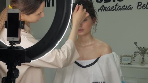 Joven hermosa mujer haciendo maquillaje en el estudio cerca de un flash de anillo — Vídeo de stock