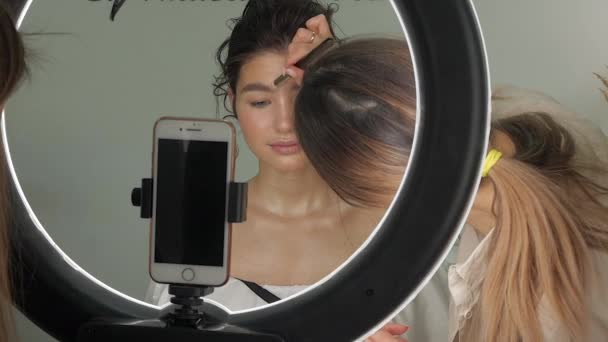 Jonge mooie vrouw doen een kapsel in de studio en het nemen van foto's op de telefoon — Stockvideo