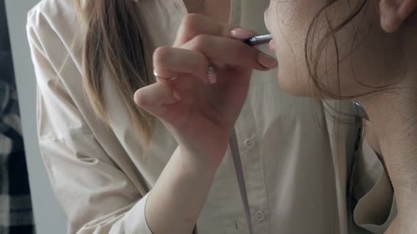 Jonge mooie vrouw aanbrengen van make-up door make-up kunstenaar — Stockvideo