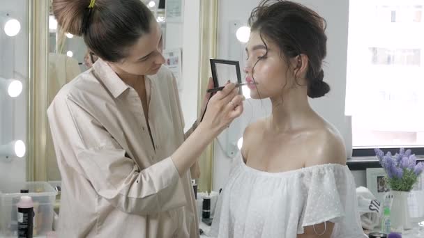 Joven hermosa mujer aplicando maquillaje por maquillador — Vídeos de Stock