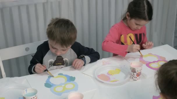 Niños niños y niñas sentados juntos alrededor de la mesa en el aula y dibujando . — Vídeos de Stock