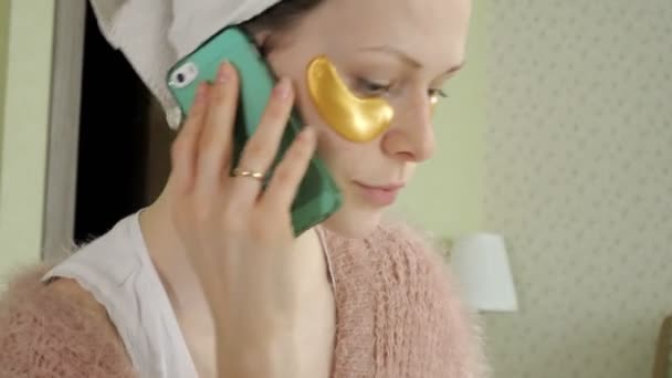 Attractive business woman applying cosmetic facial spots at home, talking on the phone — Stock Video