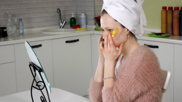 Mujer atractiva espiando parches faciales cosméticos en casa — Vídeo de stock