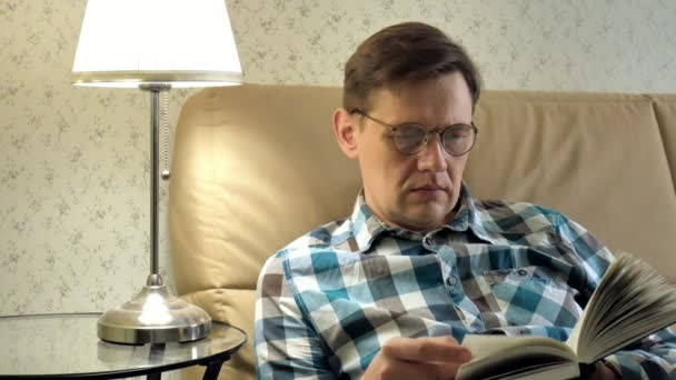 Volwassen man liggend op bed lezen van een boek thuis in slaapkamer — Stockvideo