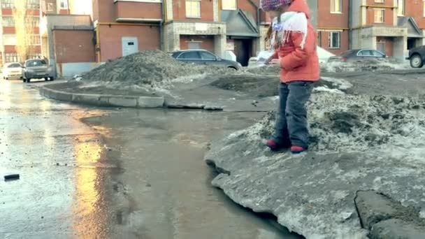 Menina em botas de borracha pulando na poça perto wite barco de papel — Vídeo de Stock