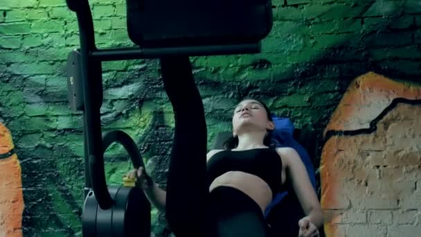 Μια ελκυστική γυναίκα κάνει εκτείνεται σε ένα προσομοιωτή σε ένα γυμναστήριο σπορ — Αρχείο Βίντεο