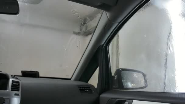 Coche que pasa a través del lavado de coches, una persona lava el coche con un fregadero sin contacto, una vista desde el interior del coche — Vídeo de stock