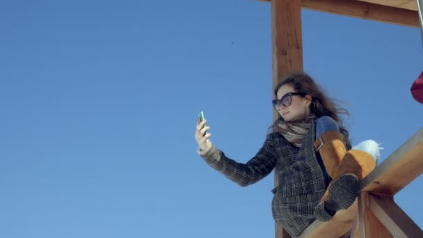 Mulher usando Smartphone Relaxa no banco em Beautiful Park. Jovem mulher em fazer gestos na tela do telefone. Tecnologia ao ar livre — Vídeo de Stock