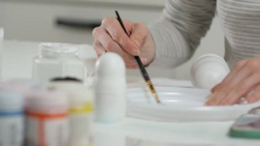 Bir kadın bir ahşap bebek renkli boyalar ile ev stüdyosunda, boyalar Matryoshka boyama, yakın çekim