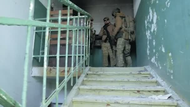 Солдаты в камуфляже с боевым оружием пробираются по коридорам старого здания, военная концепция — стоковое видео