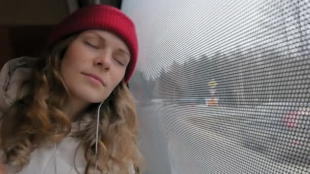 Young cheerful woman traveling by bus on a sad day. She looks out the window — Stock Video