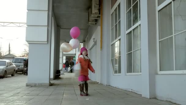 Uma menina caminhar com balões coloridos, em uma rua na cidade no início da primavera — Vídeo de Stock