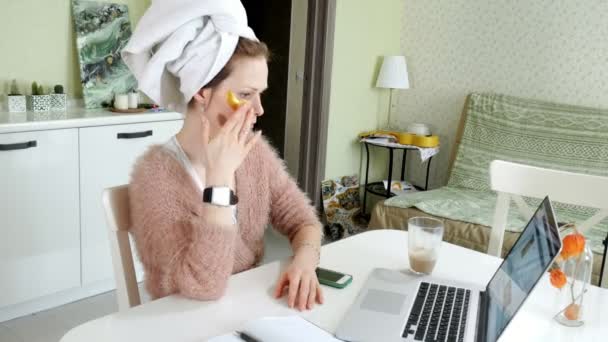 Attraktive Geschäftsfrau, die zu Hause kosmetische Gesichtsflecken aufträgt und hinter dem Laptop arbeitet — Stockvideo