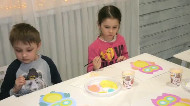 Niños niños y niñas sentados juntos alrededor de la mesa en el aula y dibujando . — Vídeos de Stock