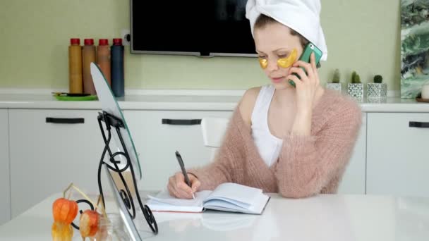 Mulher de negócios atraente aplicando manchas faciais cosméticos em casa, falando ao telefone — Vídeo de Stock