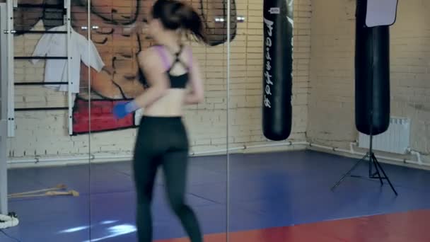 Una mujer enérgica en el boxeo en el gimnasio, entrenadores en vendas elásticas — Vídeos de Stock