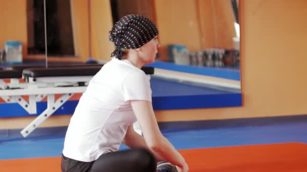 Приваблива жінка розтягується на симуляторі в спортзалі — стокове відео
