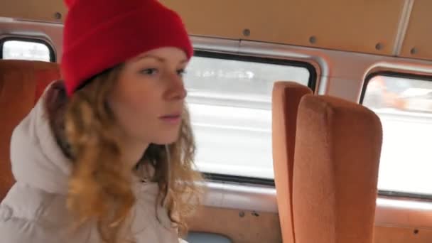 Μικρά χαρούμενα γυναίκα σε ένα κόκκινο καπέλο, ταξιδεύοντας με το λεωφορείο σε μια θλιβερή ημέρα. Αυτή ακούγοντας μουσική — Αρχείο Βίντεο