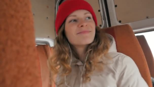 Νεαρή γυναίκα χαρούμενη Ταξιδεύοντας με το λεωφορείο σε μια θλιβερή ημέρα. Κοιτάζει έξω από το παράθυρο — Αρχείο Βίντεο