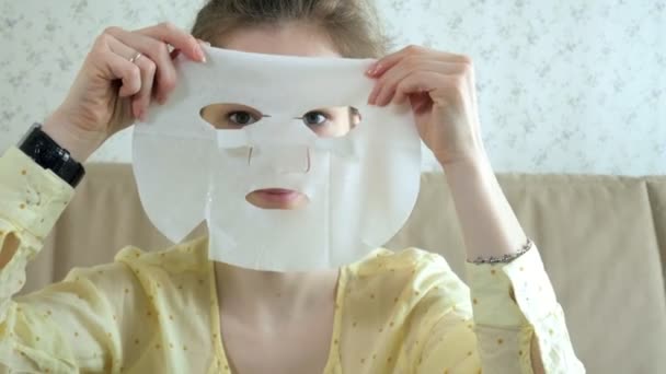 Jovem mulher fazendo máscara facial com máscara de limpeza no rosto na cozinha em casa — Vídeo de Stock