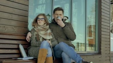 Genç kadın ve erkek bir bahar parkta bir bankta oturan bir termos şişe çay içme