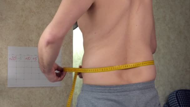 Толстяк измеряет свою талию, большой пивной живот, здоровый образ жизни — стоковое видео