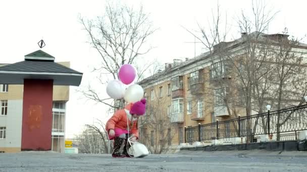 Niña hermosa saltando en charcos después de la lluvia con globos de colores — Vídeo de stock