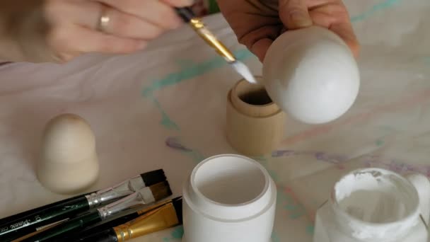 Een vrouw schildert een houten pop met gekleurde verven in haar thuisstudio, Matryoshka schilderij, Close-up — Stockvideo