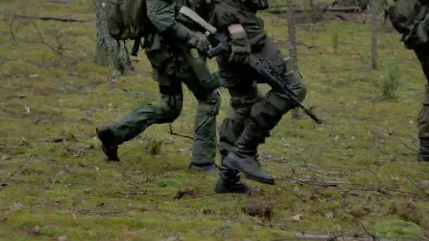 Soldados en camuflaje con armas de combate se abren camino fuera del bosque, con el objetivo de capturarlo, el concepto militar — Vídeos de Stock