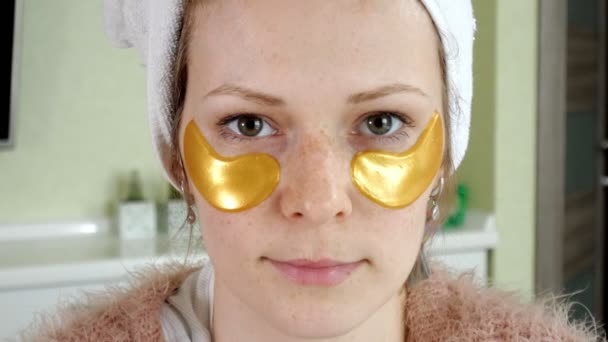 Attractive woman spplying cosmetic facial patches at home — Stock Video