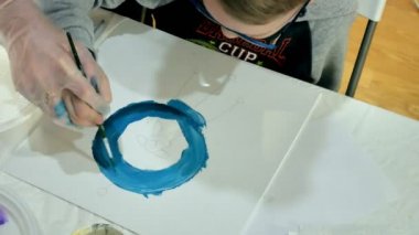 Çocuk erkek ve kız birlikte sınıf ve çizim masasının etrafında oturuyor. Onlarla birlikte onların genç ve güzel bir öğretmendir.