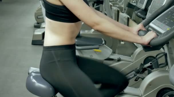 Молодая привлекательная женщина повышает выносливость во время тренировки. портрет красивой девушки в спортзале на стационарном велосипеде. молодая женщина на велотренажере аэробные упражнения — стоковое видео