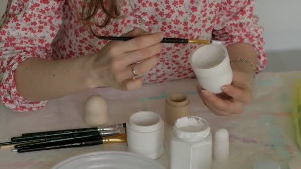 Een vrouw schildert een houten pop met gekleurde verven in haar thuisstudio, Matryoshka schilderij, Close-up — Stockvideo