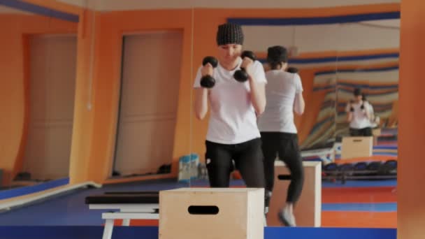 Жінка кікбоксер тренується в спортивній студії з гантелями — стокове відео