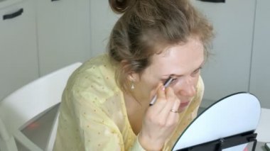 Genç güzel kadın evde bir ayna önünde makyaj.