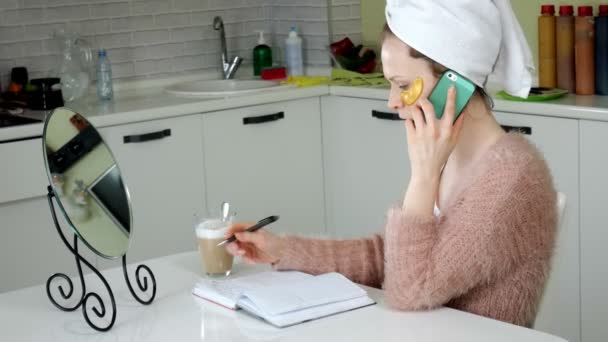 Mulher de negócios atraente aplicando manchas faciais cosméticos em casa, falando ao telefone — Vídeo de Stock