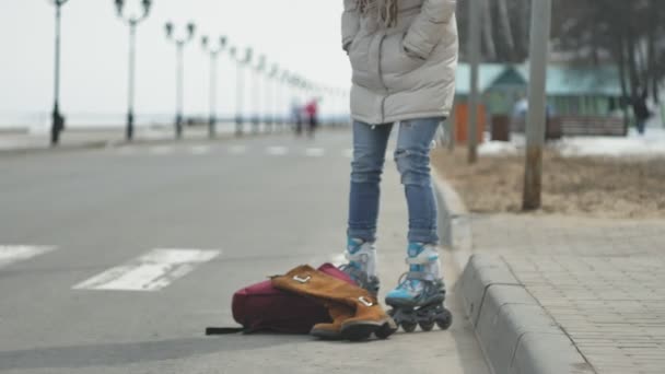 Fiatal gyönyörű nő egy piros sapkát visel, sportos meleg ruhát és a görgők, lovaglás a tengerparton úton — Stock videók