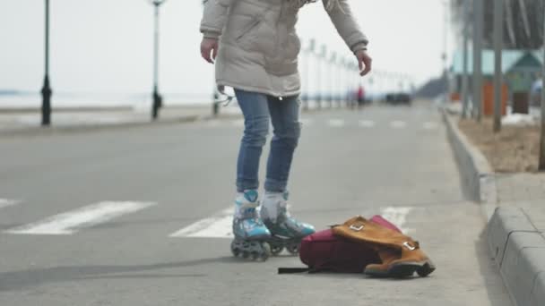 Joven hermosa mujer en un sombrero rojo, con ropa de abrigo deportivo y rodillos, a caballo en la carretera en la costa — Vídeos de Stock