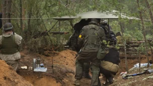 Soldados en camuflaje con armas de combate están siendo disparados en el refugio del bosque, el concepto militar — Vídeos de Stock