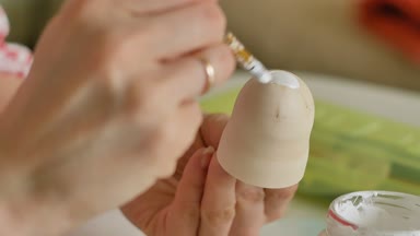 Bir kadın bir ahşap bebek renkli boyalar ile ev stüdyosunda, boyalar Matryoshka boyama, yakın çekim