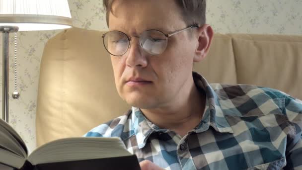 Volwassen man liggend op bed lezen van een boek thuis in slaapkamer — Stockvideo