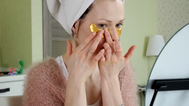 Mujer atractiva espiando parches faciales cosméticos en casa — Vídeos de Stock